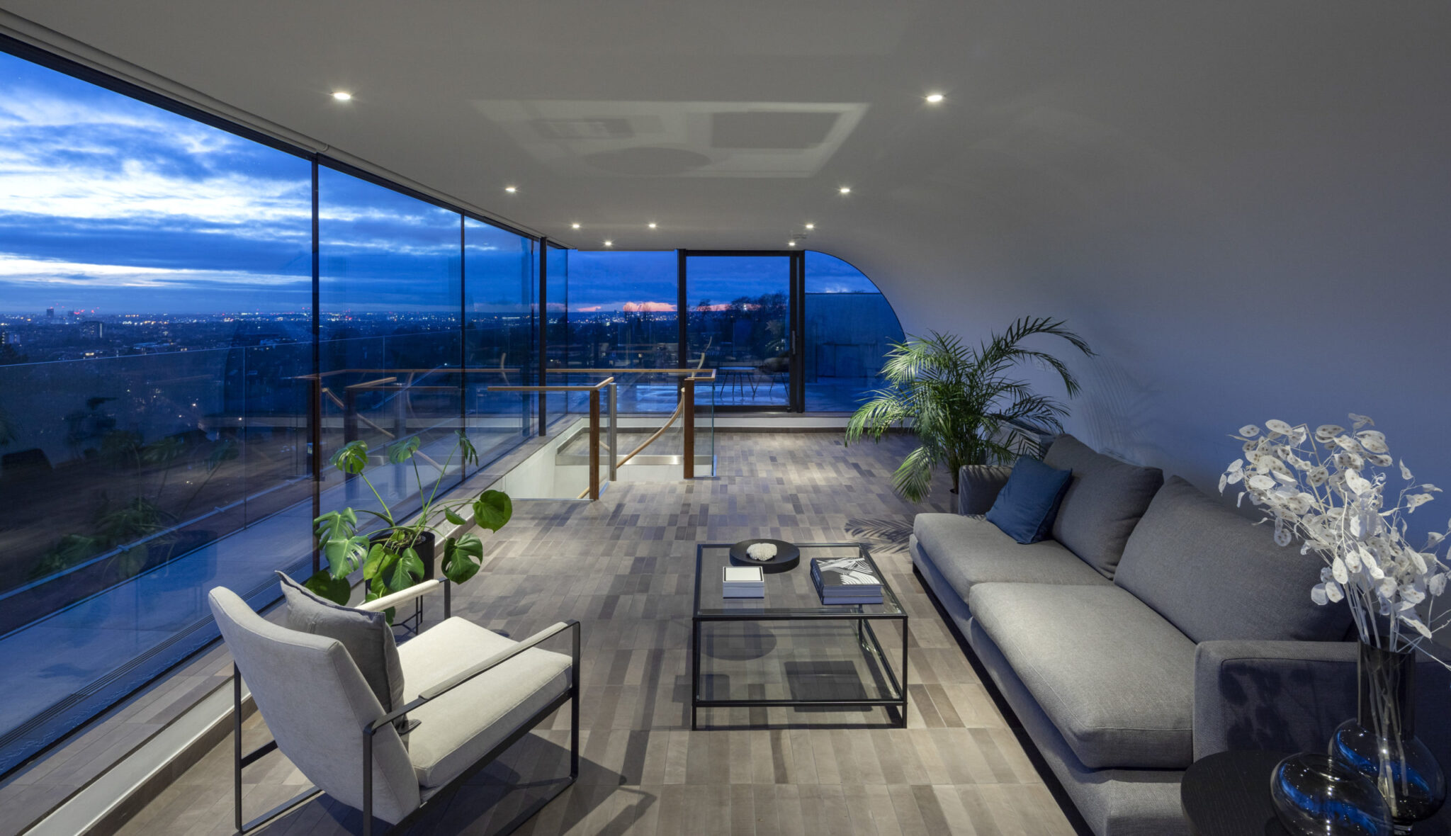 Hampstead Penthouse living room with floor-to-ceiling windows and city views at dusk